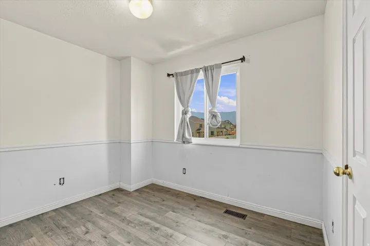 Room featuring wood-finish flooring, two-tone wall treatment, and white baseboards