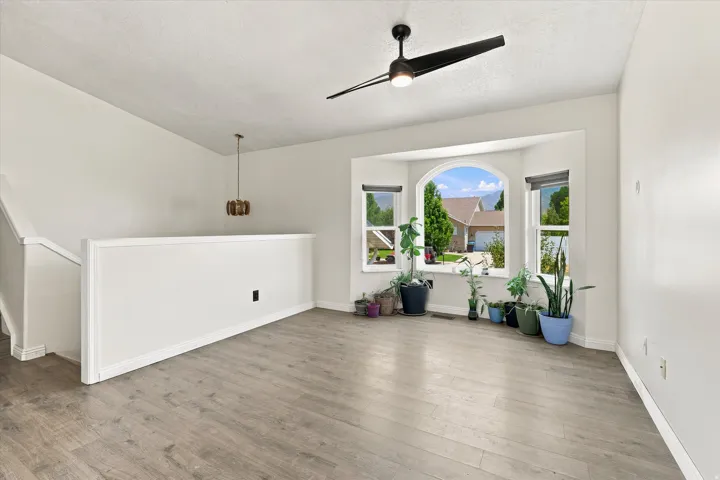 Spacious room featuring light wood-finish flooring and a contemporary black ceiling fan