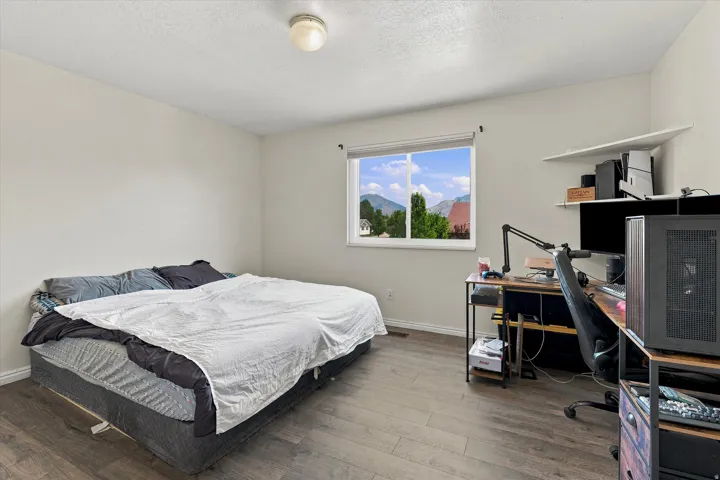 Interior room featuring wood-finish flooring, a white trim baseboard, and a window with a mountain backdrop