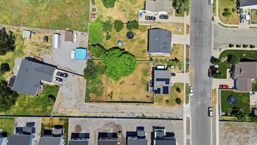 Expansive property featuring a large gravel driveway, established trees, and surrounding neighborhood streets