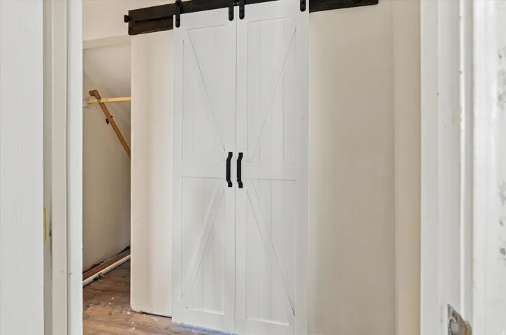 White barn doors with black hardware, mounted on a dark wood track