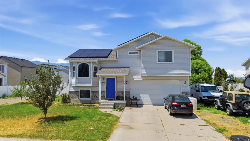 Two-story home featuring light-toned siding, a two-car garage, and a vivid blue front door