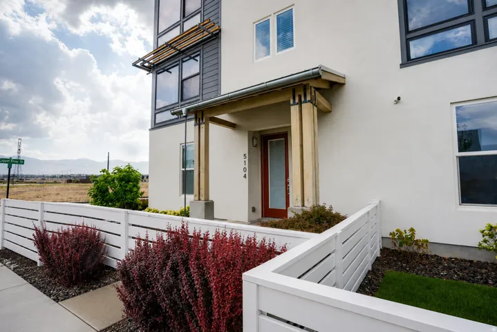 Contemporary facade with stucco siding, wood beam accents, and a distinctive red entry door