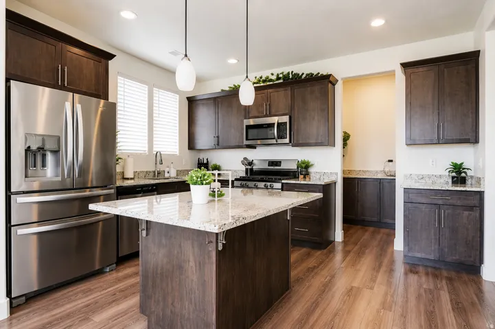 Kitchen featuring wood-finish flooring, dark wood cabinetry, light-toned countertops, and stainless steel appliances