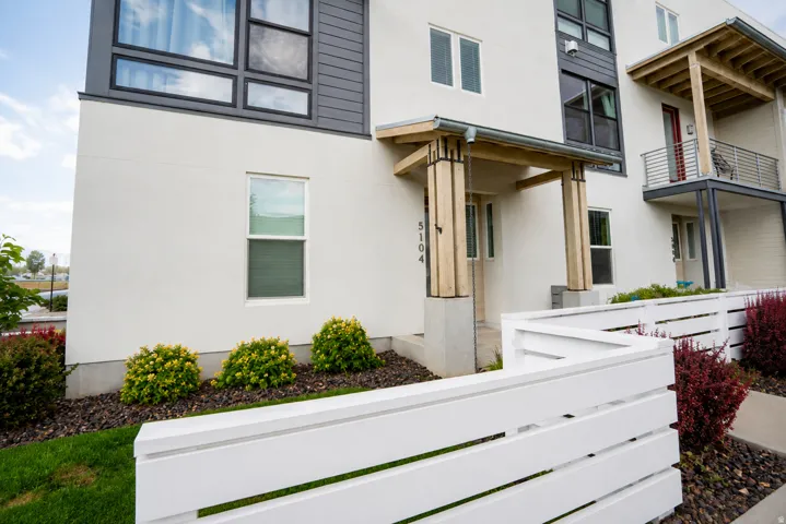 Modern exterior with white stucco siding, dark horizontal siding accents, and a covered entry featuring wood columns