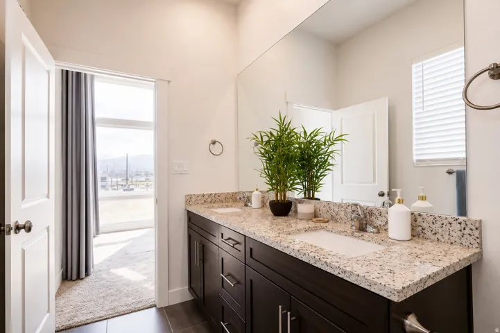 Double vanity with granite countertop, integrated sinks, and dark wood-finish cabinetry