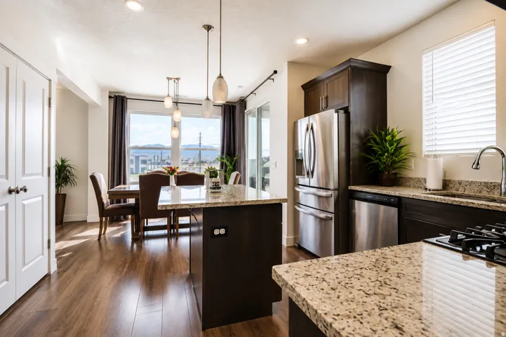 Open-concept kitchen and dining area featuring granite countertops, stainless steel appliances, wood-finish flooring, and recessed lighting