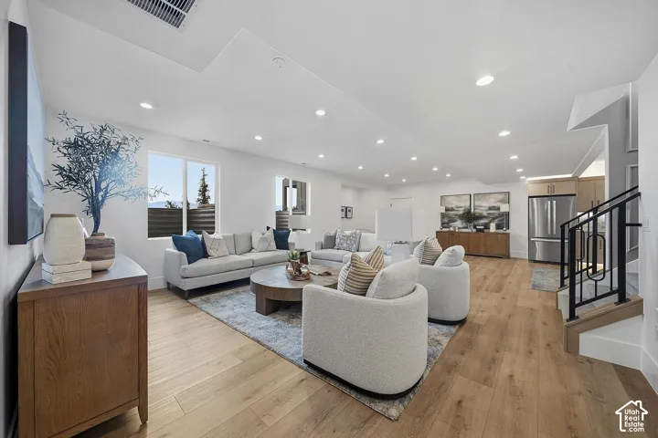Open-concept living space featuring wood-finish flooring, recessed lighting, and white walls