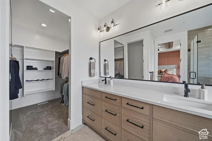 Double vanity featuring wood-finish cabinetry, white countertops, and black fixtures