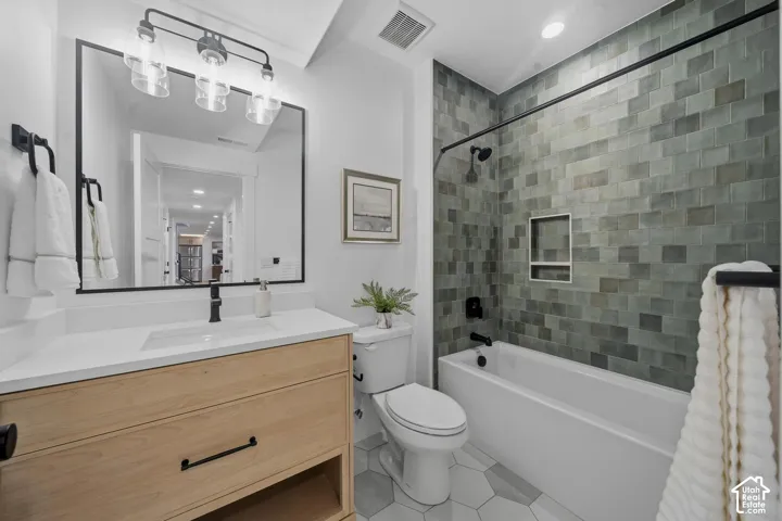 Spa-inspired bathroom featuring a wood-finish vanity with white quartz countertop, large framed mirror with integrated lighting, and matte black hardware