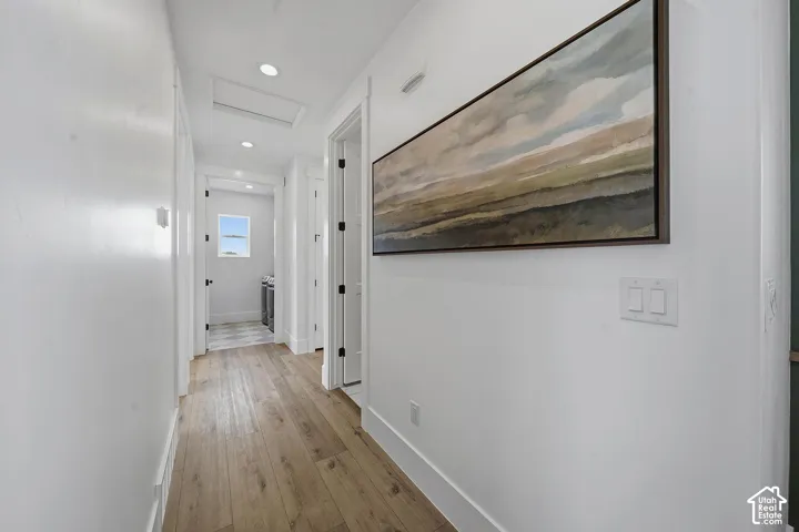 Hallway featuring wood-finish flooring, recessed lighting, and white baseboards
