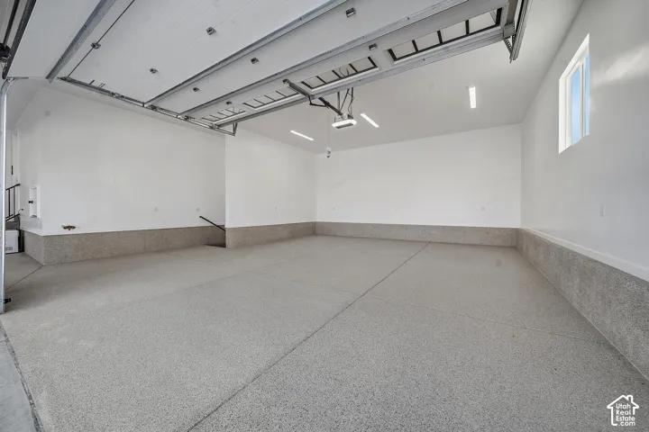 Spacious garage with an epoxy-coated floor, painted white walls, and a window for natural light