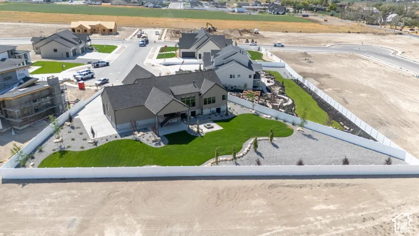 Fenced property featuring a spacious backyard with a manicured lawn, gravel landscaping, and a fire pit area