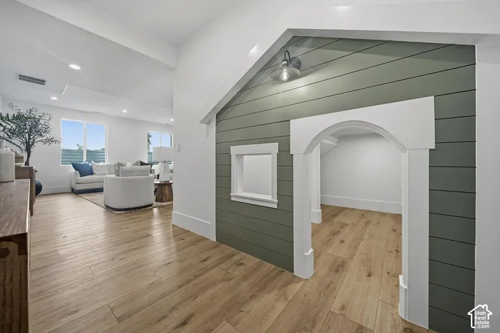Spacious open-concept living area featuring wood-finish flooring throughout, recessed lighting, and large windows with natural light