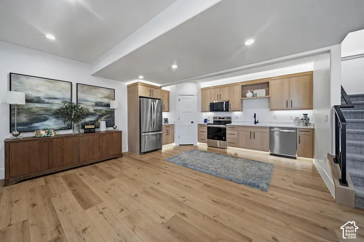 Kitchenette featuring light wood-finish cabinetry, stainless steel appliances, and a white countertop