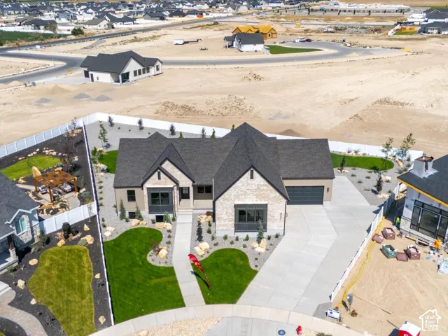 Contemporary residence featuring a paved driveway, attached garage, stone and stucco exterior, and a landscaped front yard with a stone pathway
