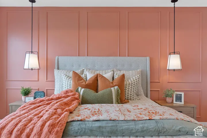 Accent wall with decorative molding, featuring a light gray upholstered headboard, and two pendant light fixtures