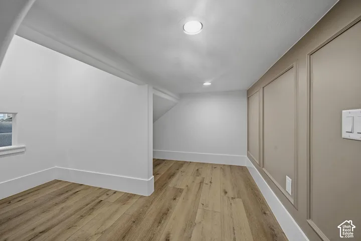 Room featuring wood-finish flooring, recessed lighting, and white baseboards