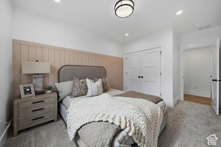 Bedroom featuring a panel accent wall, recessed lighting, and soft carpet flooring