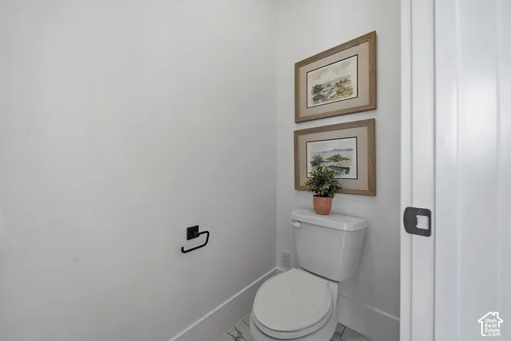 White toilet with matte black hardware, framed by white walls and a white paneled door