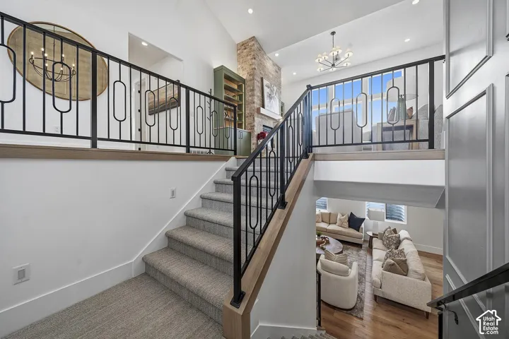 Dramatic two-story foyer showcasing a floating staircase with wood-finish treads and black metal railing, anchored by a stone accent wall and pendant lighting