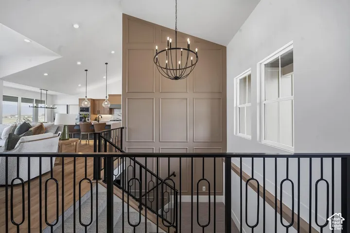 Open concept upper-level landing featuring a vaulted ceiling and a contemporary chandelier