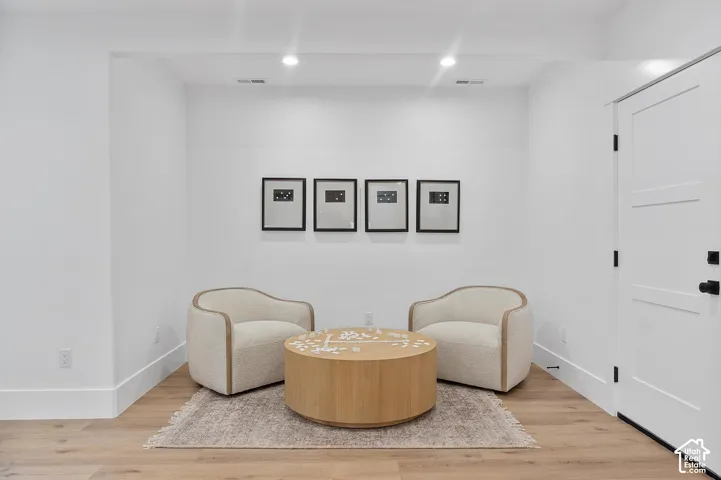 Sophisticated lounge featuring two upholstered accent chairs with curved backs and nailhead trim, positioned around a round wood-finish center table