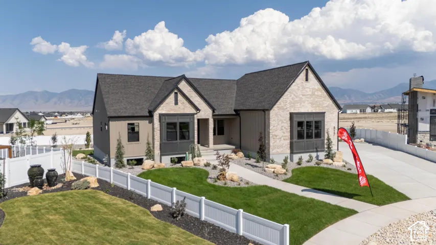 Modern two-story residence featuring a light-colored brick and stone exterior with peaked rooflines and architectural detailing
