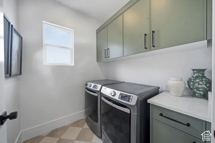 Dedicated laundry space featuring checkerboard pattern flooring, a single window, and light green cabinetry with matte black hardware