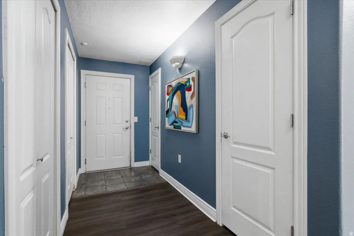 Entryway featuring wood-finish flooring, a white paneled entry door, and light blue wall tones