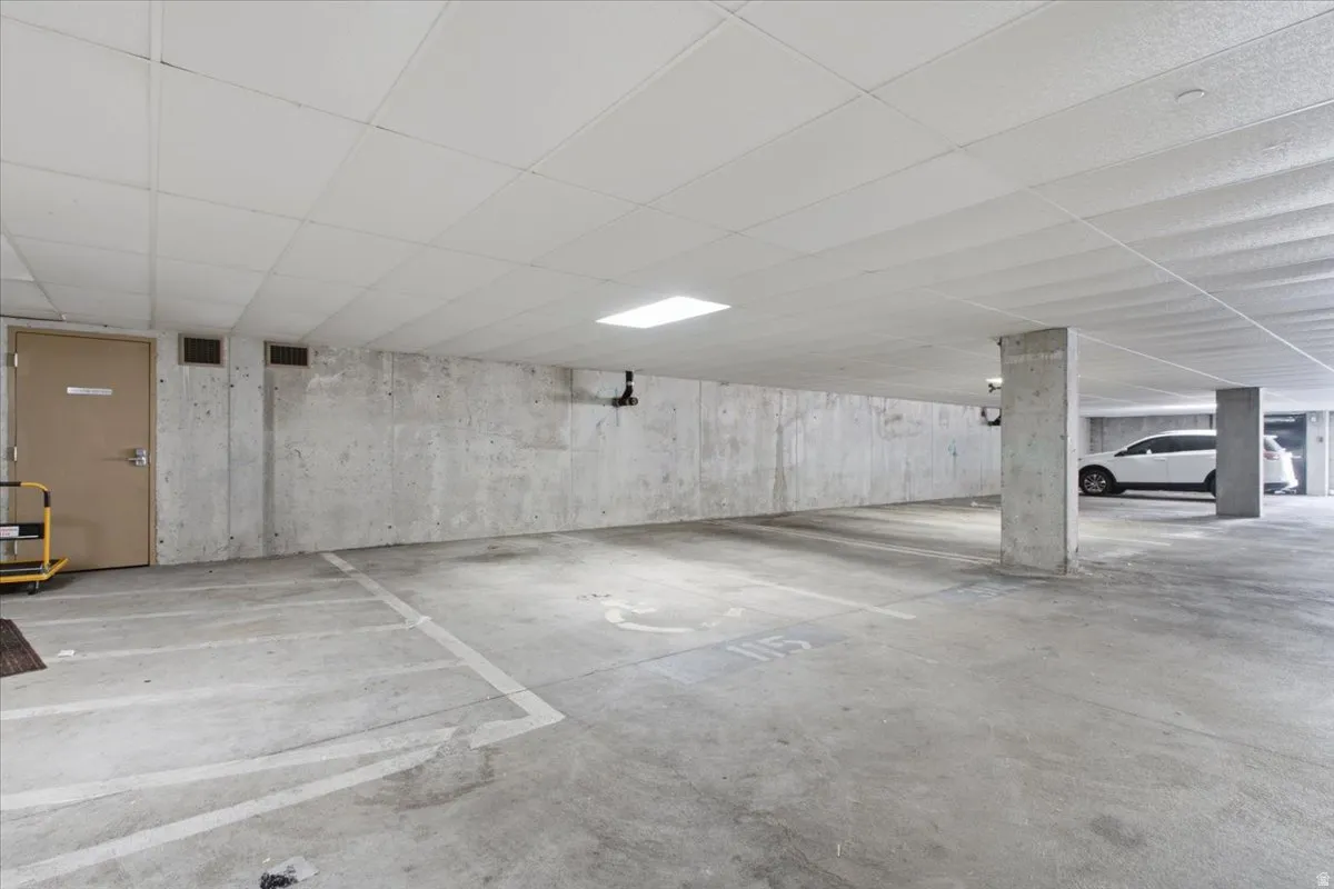 Dedicated parking space with concrete flooring, exposed concrete walls, and overhead lighting