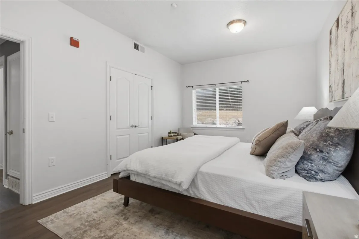 Spacious room featuring wood-finish flooring, white walls, and a ceiling-mounted light fixture