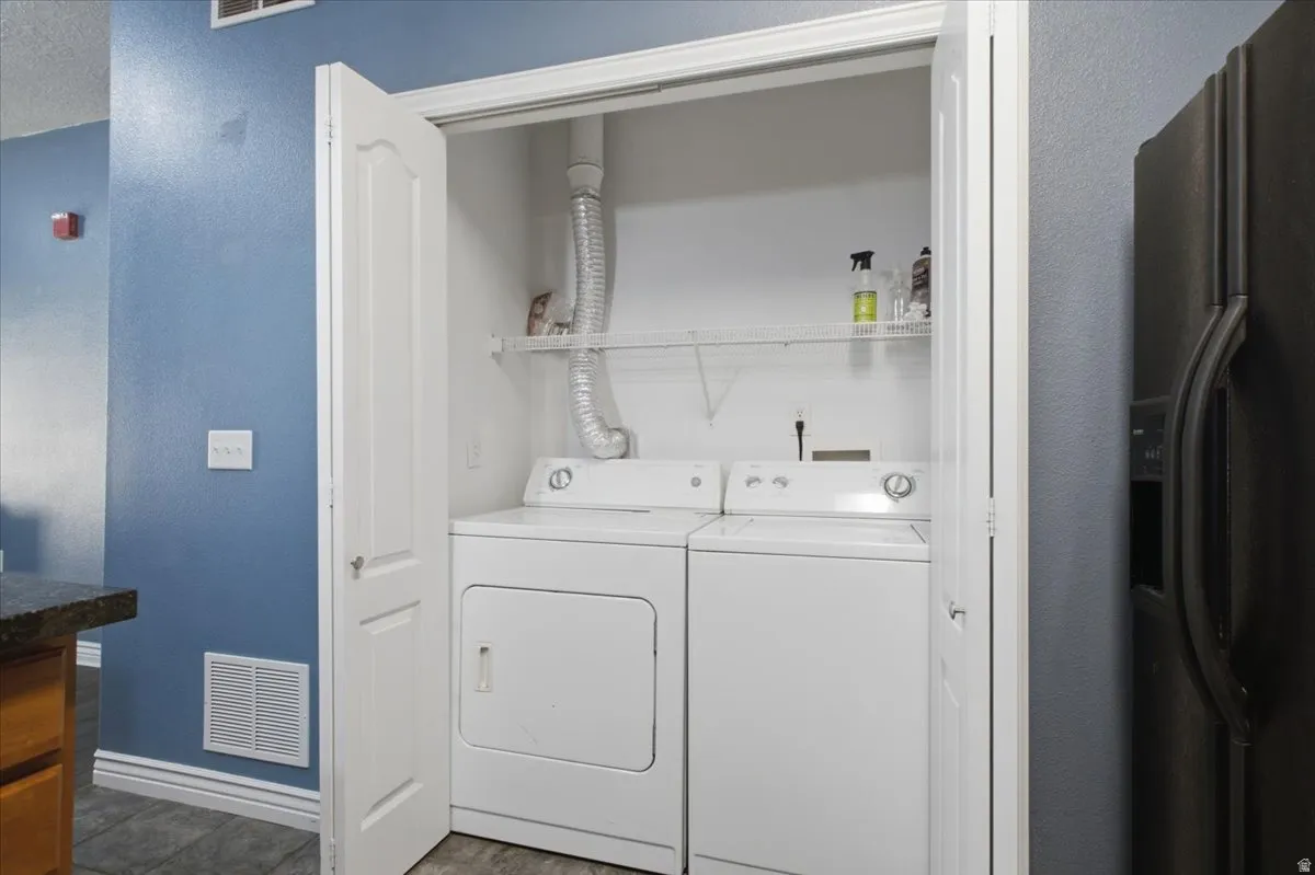 Laundry closet with bi-fold doors, stacked white washer and dryer, and wire shelving