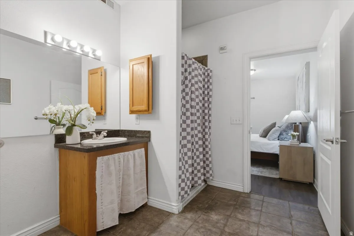Bathroom featuring a wood-finish vanity with a dark countertop and an undermount sink