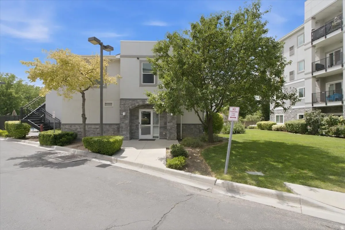 Multi-story building exterior featuring a stone facade at the base, stucco siding, and a prominent arched entryway
