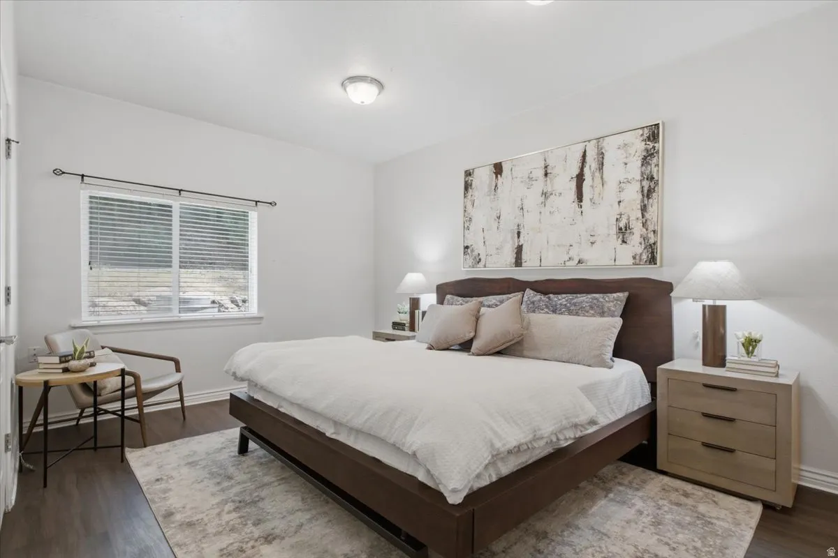 Spacious room with wood-finish flooring, a contemporary overhead light fixture, and a large window with white blinds
