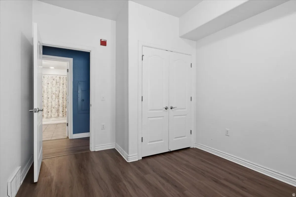 Spacious room featuring wood-finish flooring and white baseboards