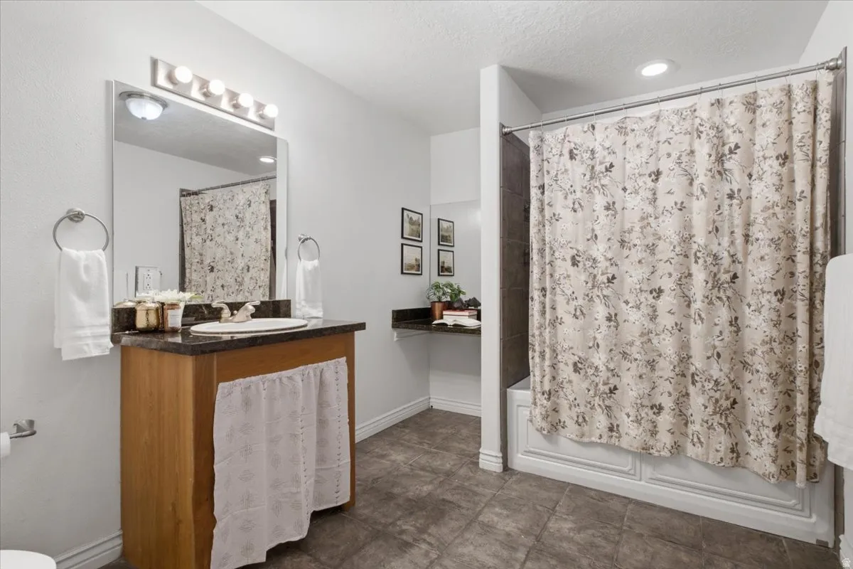 Bathroom featuring a built-in wood vanity with a granite-style countertop and undermount sink