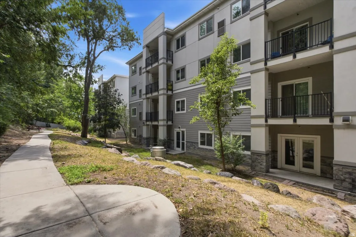 Multi-story structure featuring a modern exterior with varied siding, balconies with dark railings, and a stone base