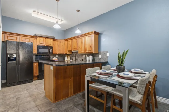 Kitchen featuring wood cabinetry, black appliances, dark countertops, and tile flooring