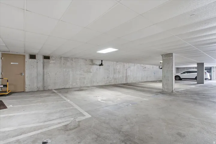 Dedicated parking space with concrete flooring, exposed concrete walls, and overhead lighting
