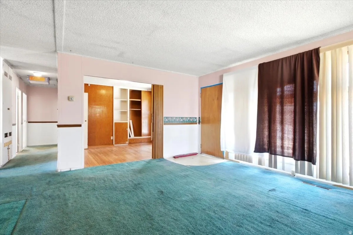 Spacious room with teal carpeting and soft pink walls