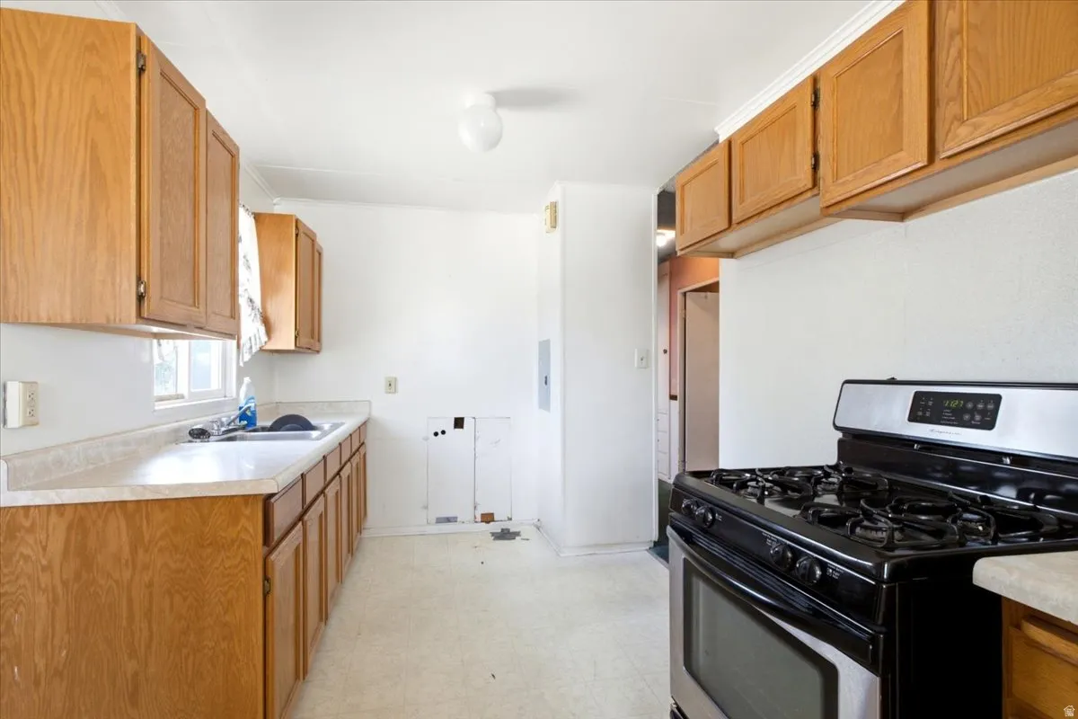 Kitchen featuring wood cabinetry, laminate countertops, a stainless steel and black range, and an integrated sink with window