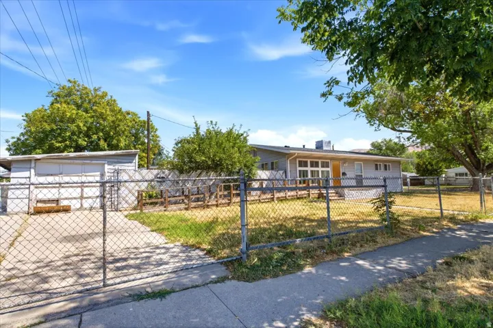 Fenced property featuring a concrete driveway, a separate storage building, and a main residence with a sloped roofline and exterior wood deck