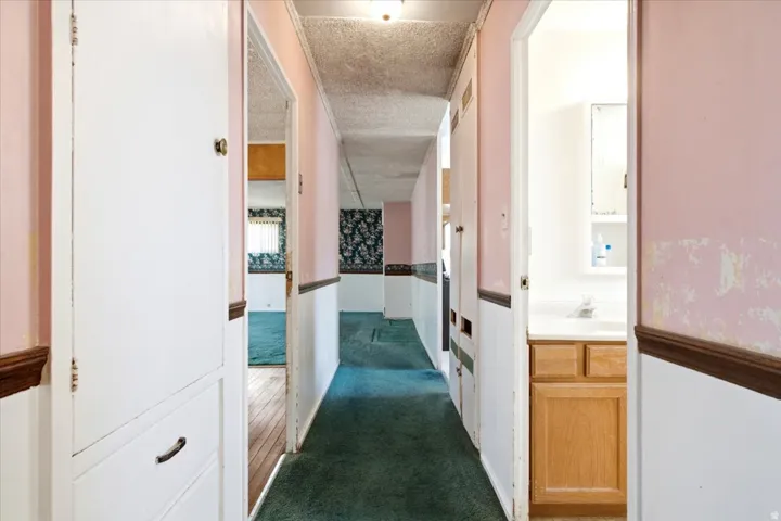Hallway featuring built-in cabinetry, wood trim, and a glimpse into a bathroom with a vanity and mirror