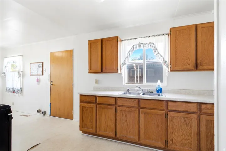 Kitchen area featuring wood-finish cabinetry, a double basin stainless steel sink, and light-toned countertops