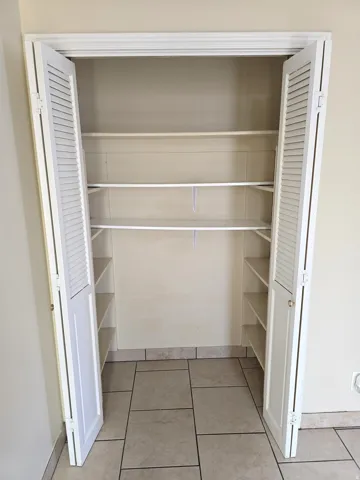 Louvered bifold doors open to a built-in closet system featuring multiple shelves