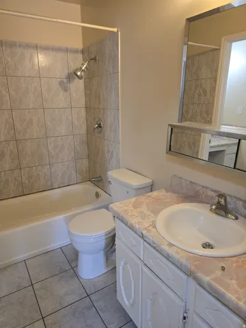 Bathroom featuring a full vanity with an integrated sink, white cabinetry, and a patterned countertop