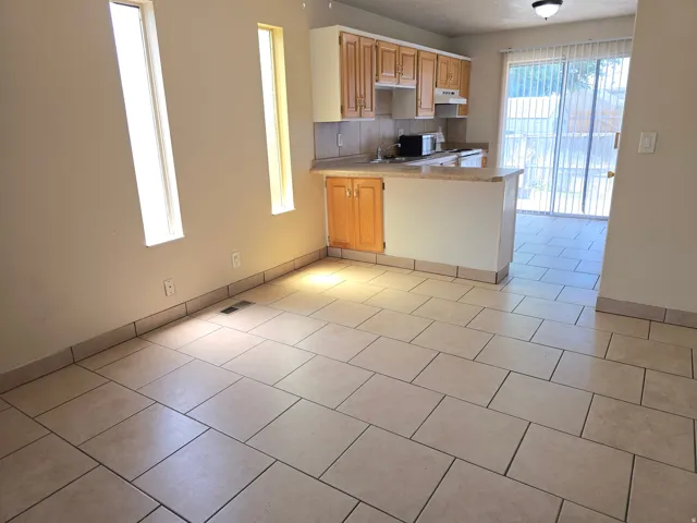 Expansive room featuring light-toned tile flooring, two vertical windows, and a built-in breakfast bar with a light-toned countertop
