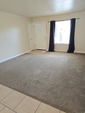 Expansive carpeted living area with neutral wall tones and white baseboards